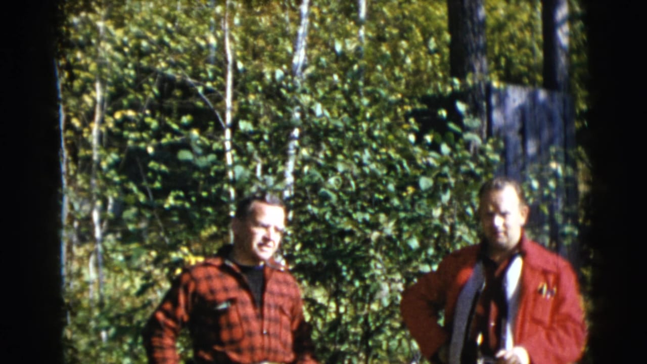 The men remain standing outdoors in 1953 Baraboo footage, framed by birch trunks and sunlit greenery.