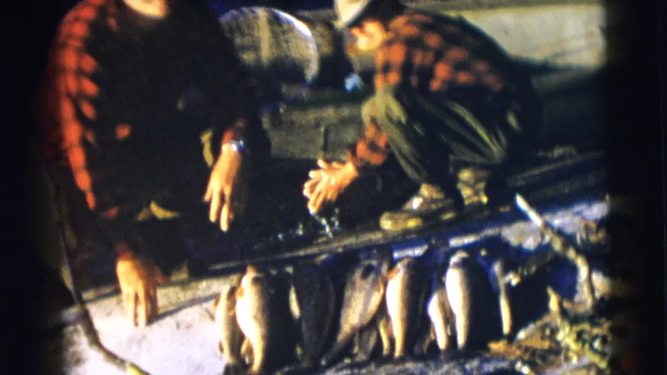 1953 Baraboo, Wisconsin 8mm frame with two men in a boat and a row of fish across the foreground.