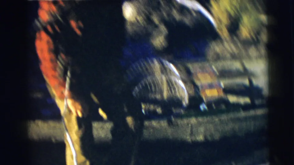 A soft, motion-blurred 1953 Baraboo home-movie frame shows a man beside a boat with fishing gear and water in the background.