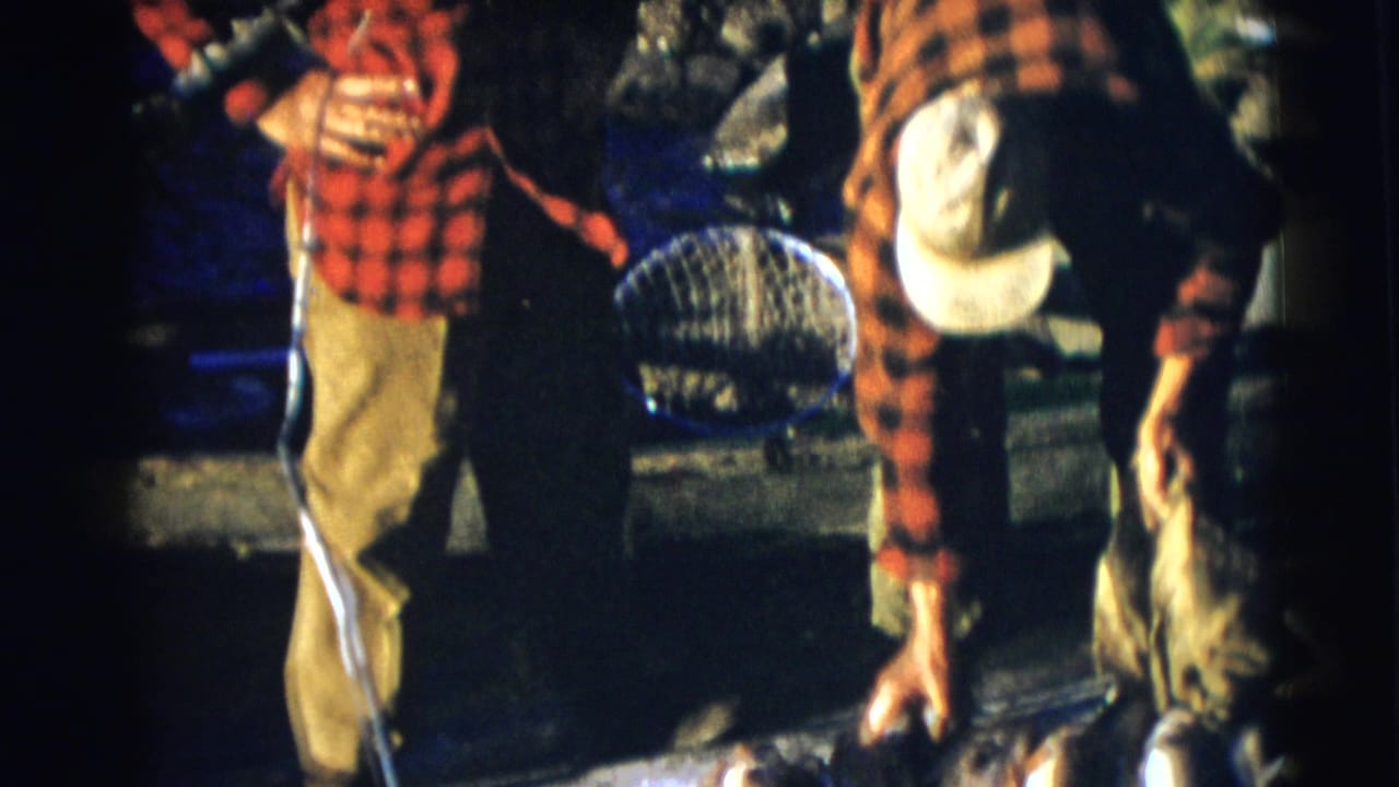 Men in plaid shirts stand by a boat at night while handling fish and gear.