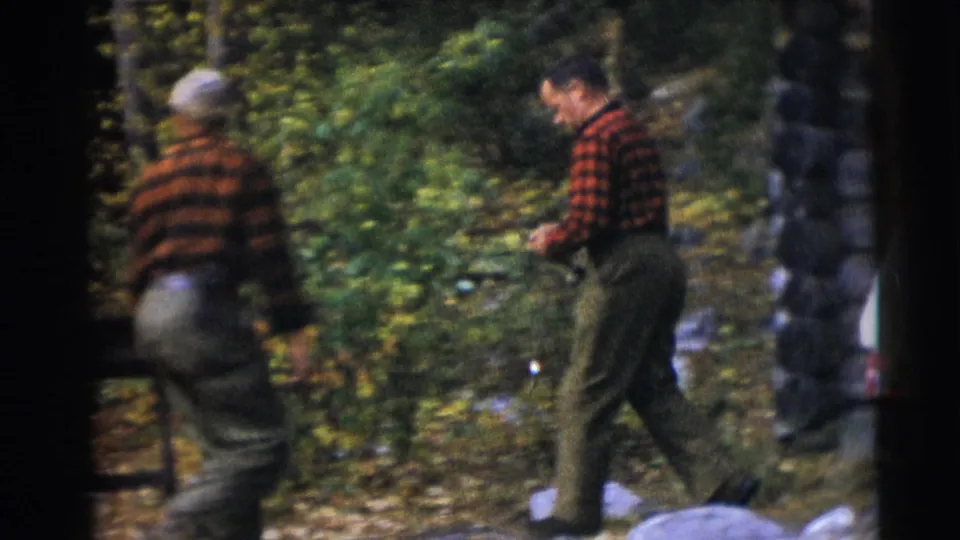 Two men in plaid shirts walk through autumn woods in the Baraboo, Wisconsin home-movie scene.