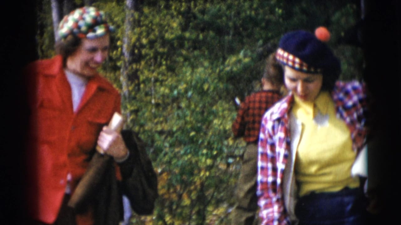 Two women in colorful 1950s-style outdoor clothing walking in a wooded area.