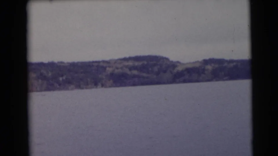 1953 Baraboo, Wisconsin lake view with a broad water surface and low wooded hills across the horizon.