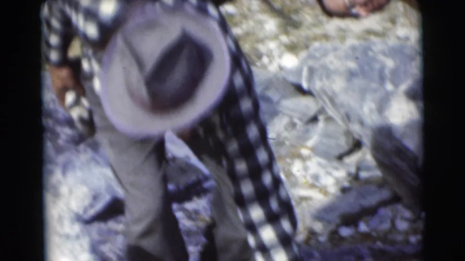 The flannel-shirted man leans low over rocks in the Baraboo, Wisconsin woodland footage from 1953.