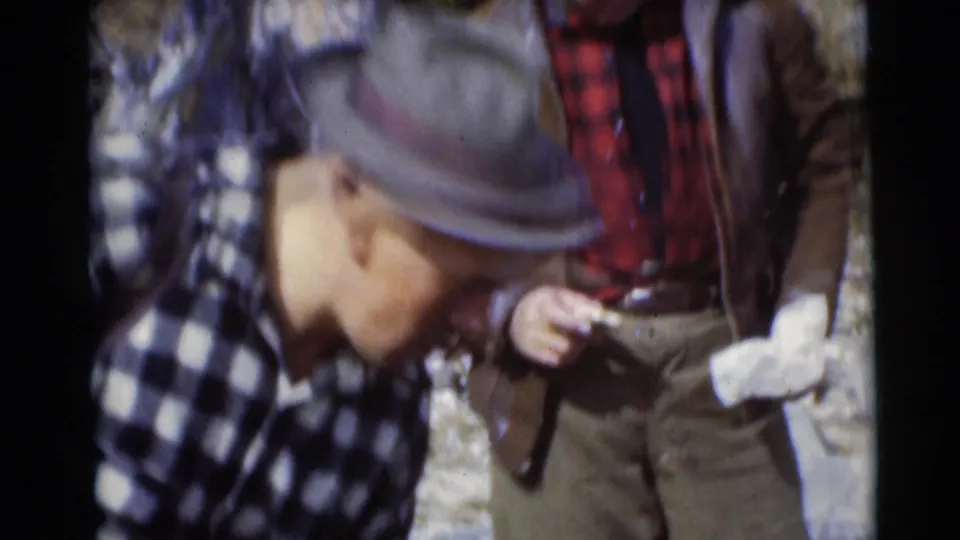 Two adult men in hats and plaid shirts stand together in the 1953 Baraboo, Wisconsin camping scene.