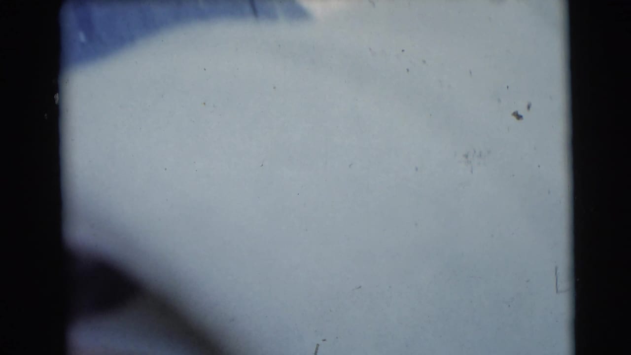 Soft close view of a pale blanket or bedding in dim blue-gray shadow.