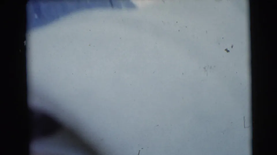 1953 Baraboo home-movie frame showing a pale blanket-like surface in soft focus with dark film borders and muted light.