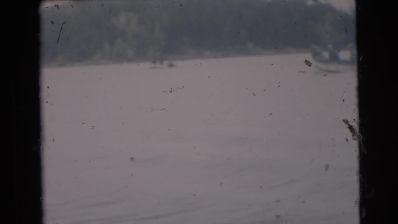 Hazy lake view with distant shoreline and visible film scratches.