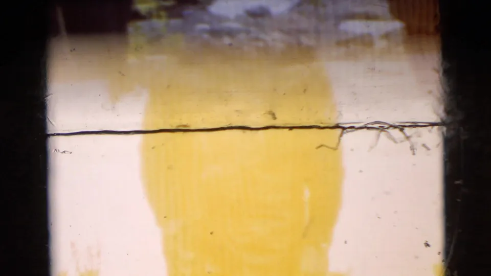 1956 Miami 8mm frame with a faint standing figure, yellow fading, shoreline detail, and a prominent horizontal film mark.