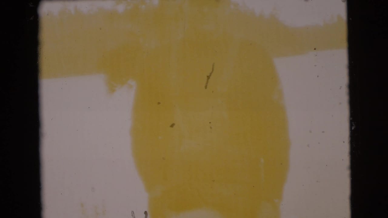 Yellow-tinted blurred film frame with dark 8mm borders.
