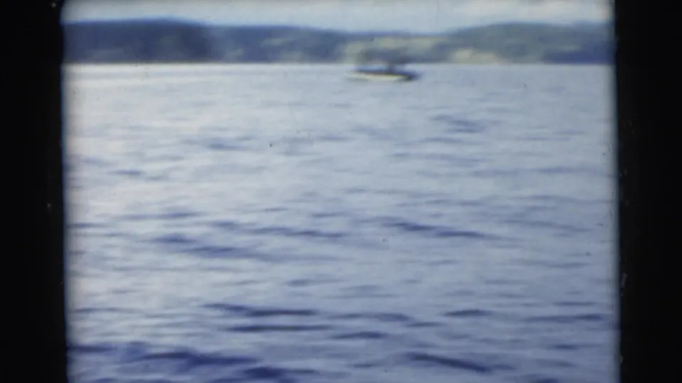 1956 Miami-area 8mm frame showing open water, distant shoreline, and a small boat barely visible near the horizon.