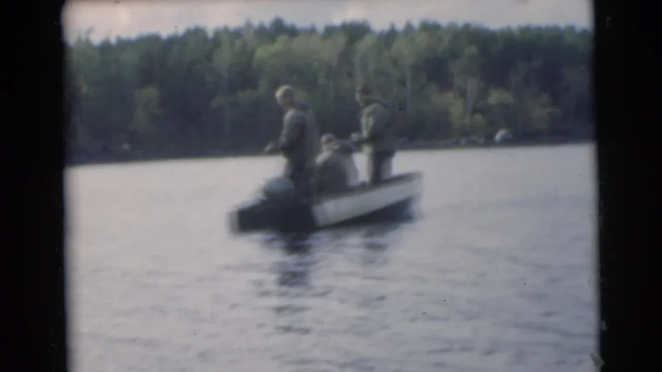 Three men ride in a small motorboat on a wooded Miami lake in 1956 archival home-movie footage.