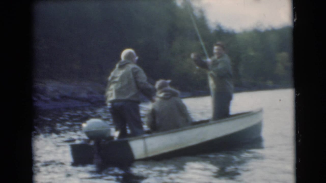 Three adult men fishing from a small motorboat near a wooded shoreline.