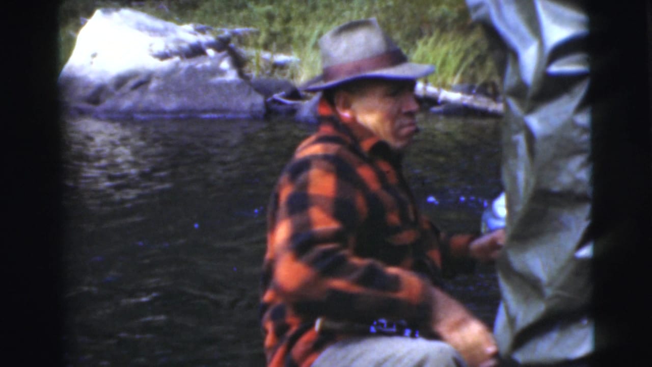 Man in plaid jacket turns in the boat while another person stands partly in frame.