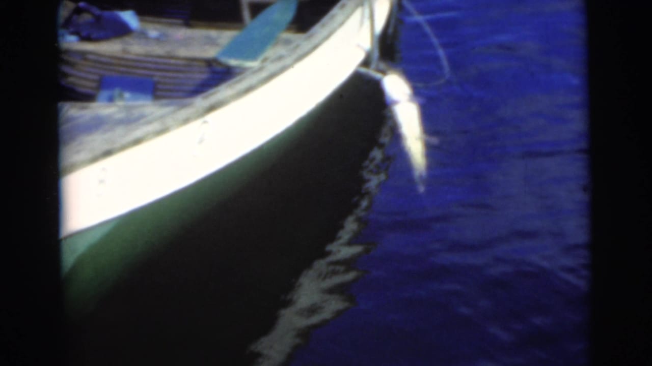 Close view of a small boat hull floating on dark blue water.