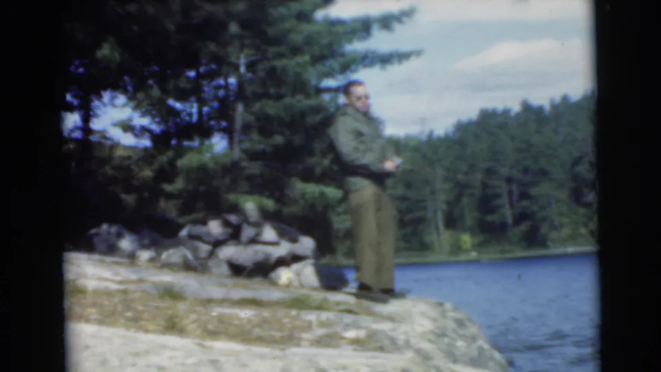 The final frame shows the man on the rocky lakeshore with fishing rod in hand, lake water and dense trees behind him.