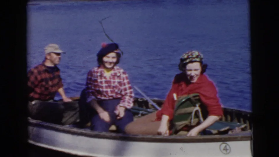 The final frame shows three adults seated in a small boat on blue water in metadata-supported 1956 Miami footage.
