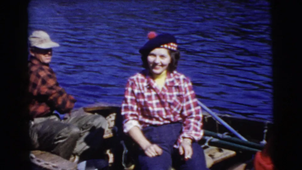 Home-movie view of a man and woman seated in a small boat on a sunny Miami lake, with visible 8mm color and grain.