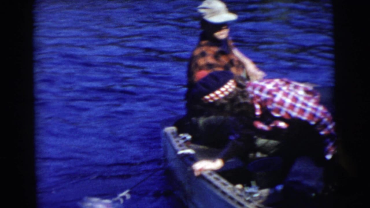 People in a small boat on blue water as one person leans near the side.