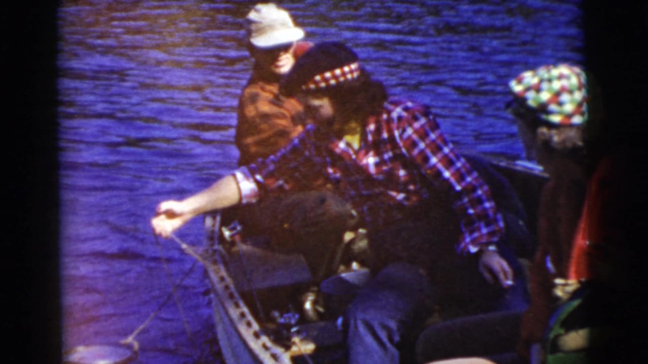 Woman in a plaid shirt holds a fishing line from a small boat.