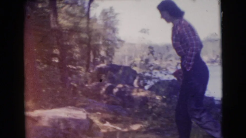 1956 8mm frame showing the woman moving through a wooded lakeside area in Miami, Florida.