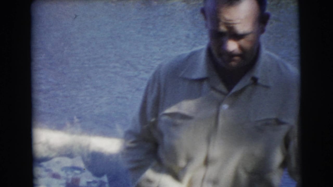 Man in a light shirt standing outdoors in soft focus.