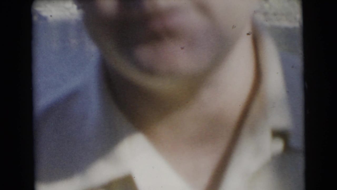 Soft, blurred close-up of an adult man in a light shirt, likely from the same 1956 Miami outdoor home-movie sequence.