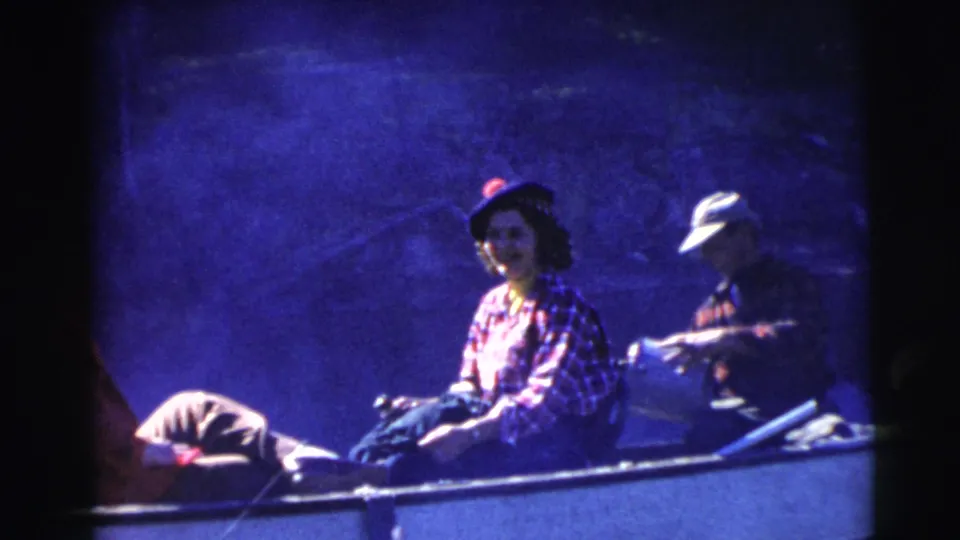 1956 Miami frame showing a woman in a plaid shirt seated in a rowboat, with another passenger and oars nearby.