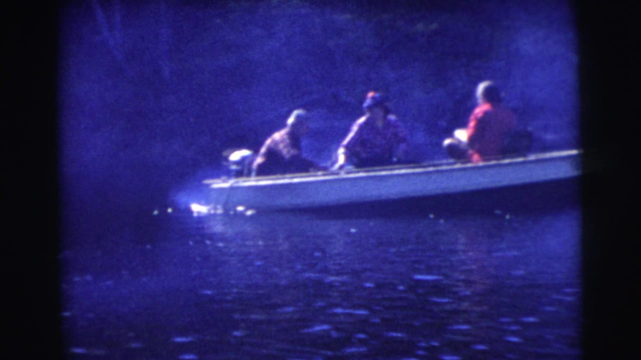 Three people sit in a small motorboat on dark blue water.