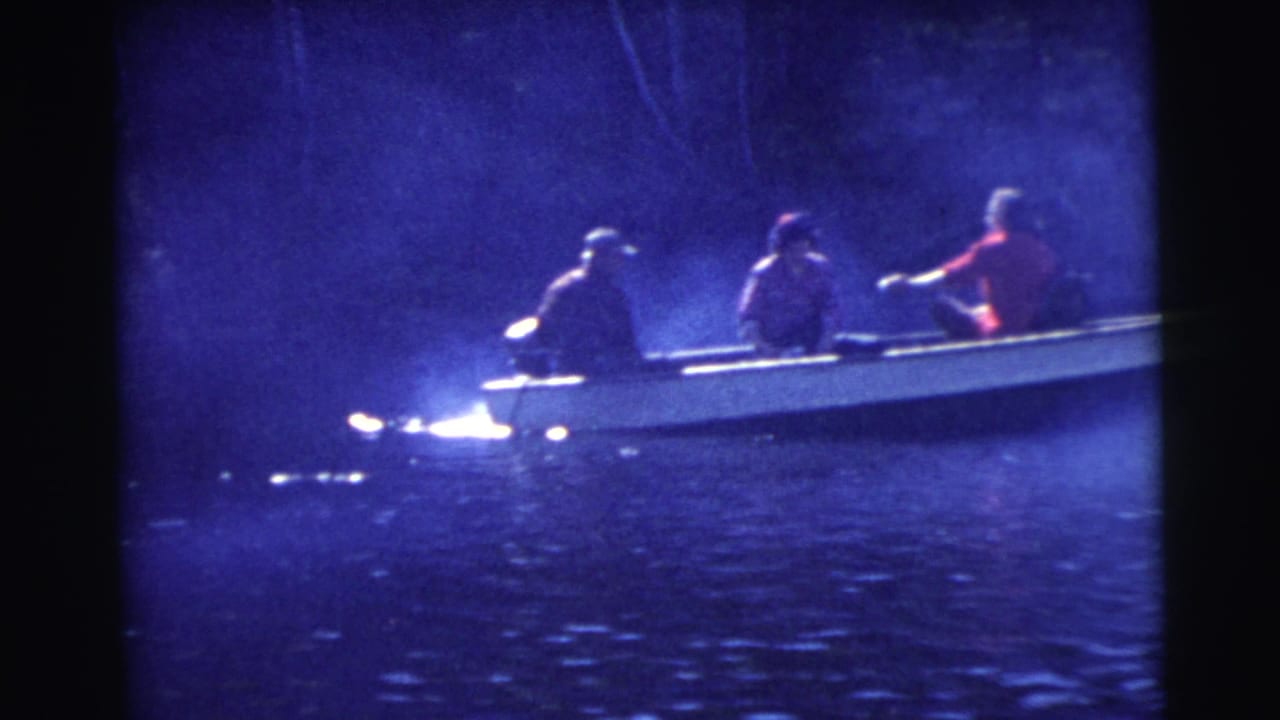 A small motorboat moves across water with three seated passengers.
