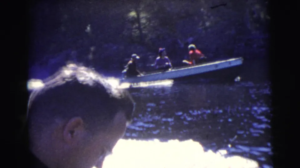 1956 Miami home-movie frame from one boat, with a man's head in the foreground and another small motorboat behind him.