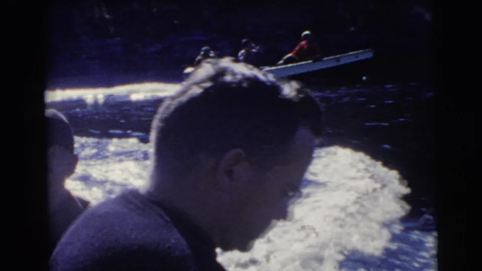 1956 Miami frame with a foreground male passenger and a small motorboat carrying several people in the background.