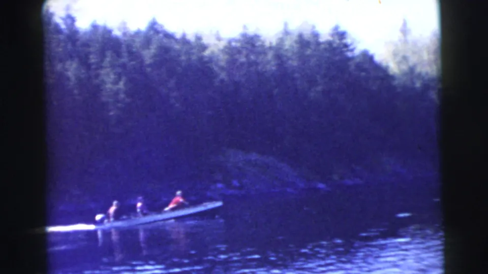 Small motorboat with multiple riders moves left to right on a wooded Miami-area waterway in 1956 footage.