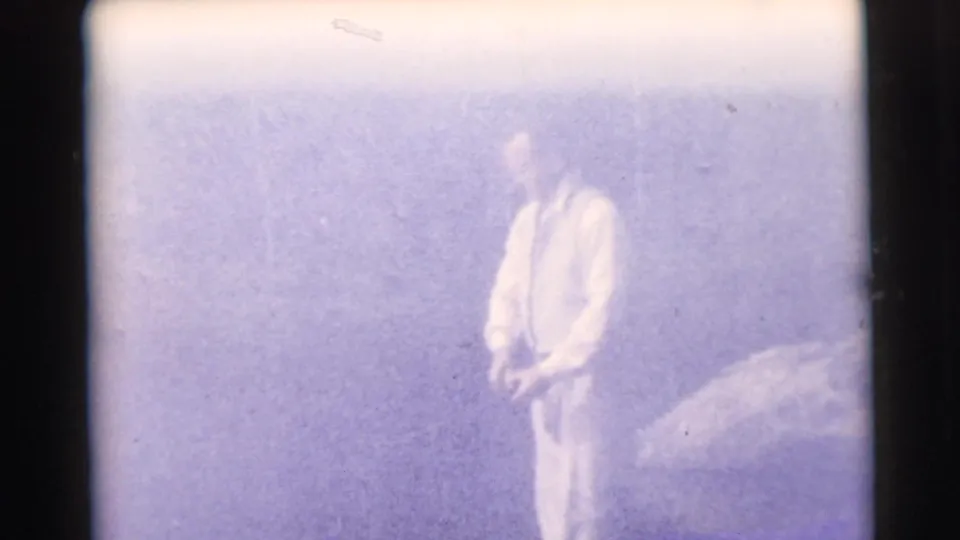A man appears to stand by the water with fishing gear in a pale, overexposed 1956 Miami home-movie frame.