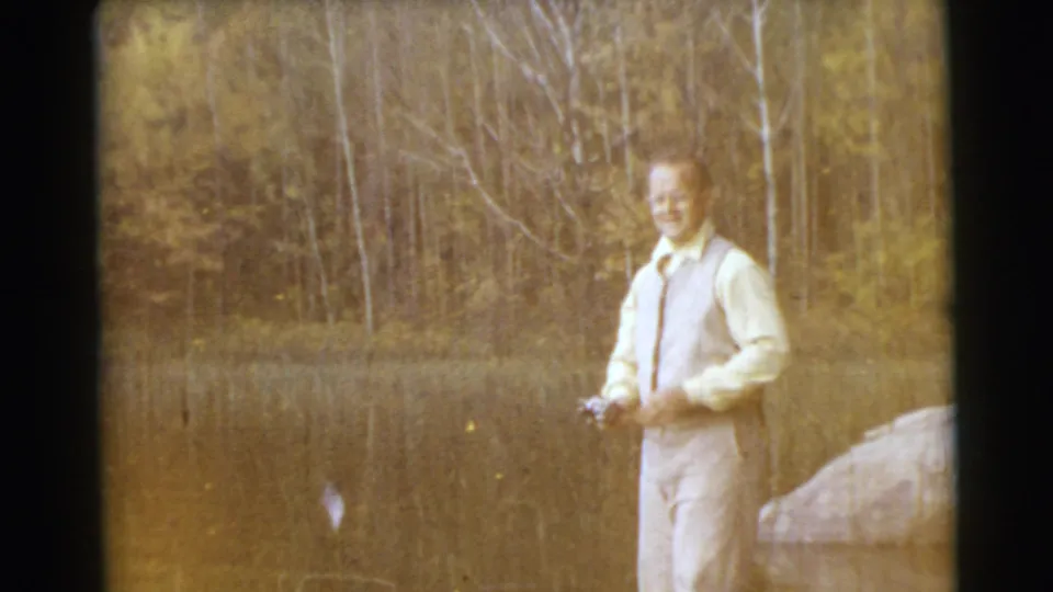 In the 1956 Miami lakeside shot, the man turns toward the camera while holding his fishing rod, with trees and water behind him.