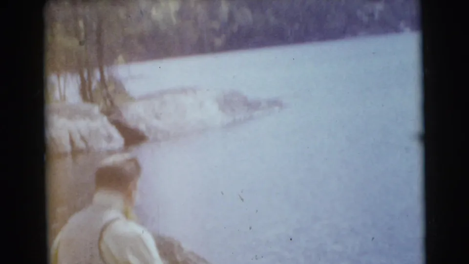 The final frame shows the man from behind at the lakeshore, looking across pale water toward a wooded bank in the Miami footage.