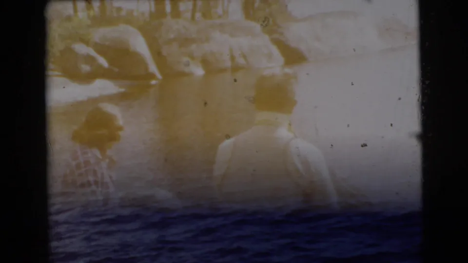 A transition-like 8mm frame shifts from the seated lakeside pair toward a wider water or sea view.