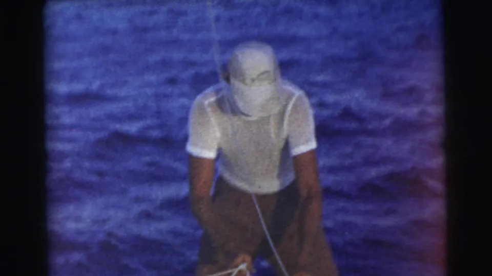 The man leans forward in the 1956 Miami home movie, concentrating on a rope with open blue water behind him.