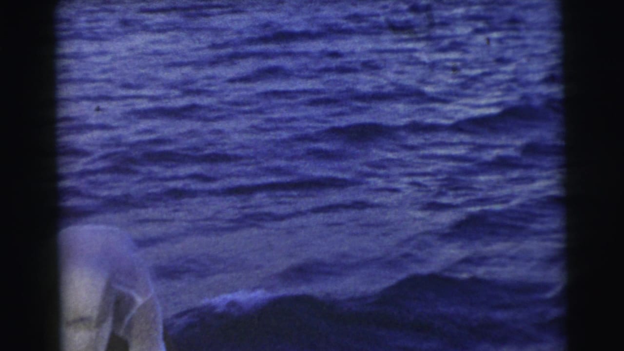 1956 Miami footage frame with a partial figure at the lower edge and open blue water dominating the view from a boat.