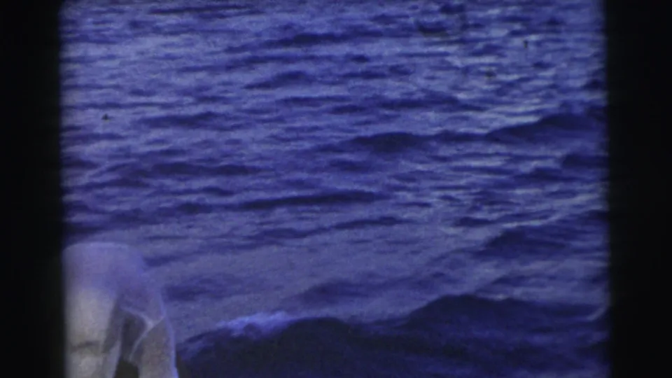 1956 Miami footage frame with a partial figure at the lower edge and open blue water dominating the view from a boat.