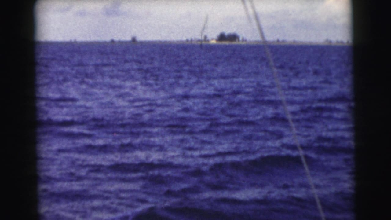 Choppy blue ocean with a distant low island on the horizon and a diagonal line across the frame.