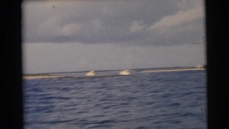 1956 Miami-area 8mm footage shows small boats crossing choppy blue water near a distant sandy shoreline.