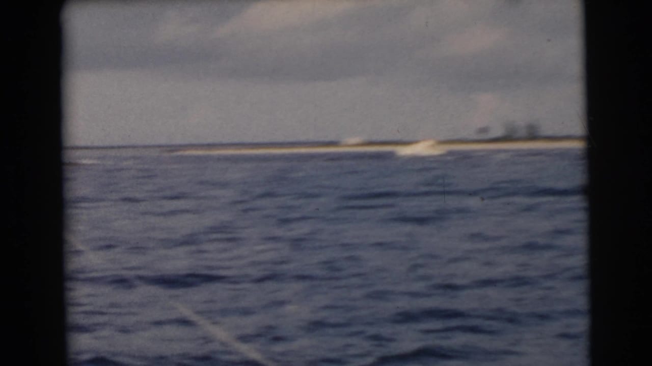 Open blue water with a low shoreline and small pale shape near the coast.