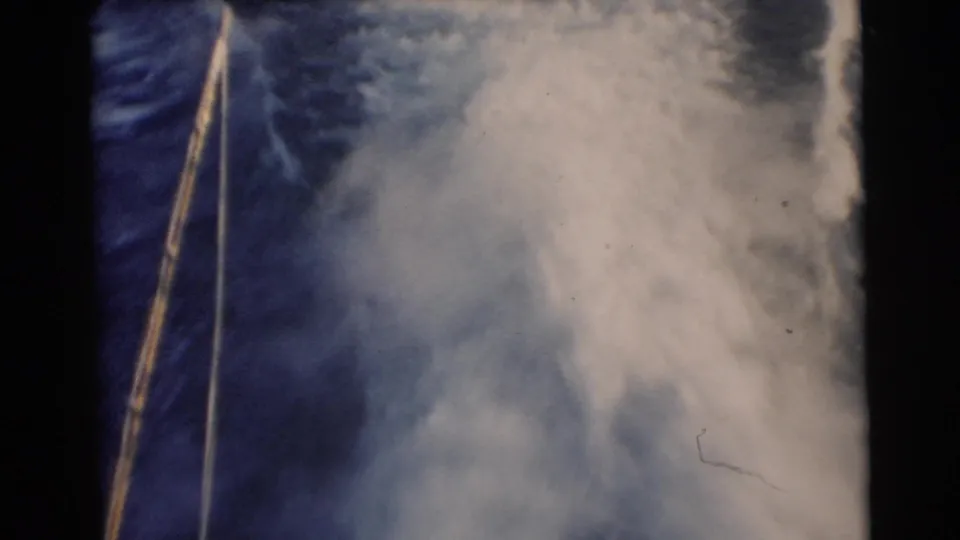 1956 Miami 8mm home-movie frame showing deep blue water, foamy wake, and a diagonal tow rope during water-skiing action.