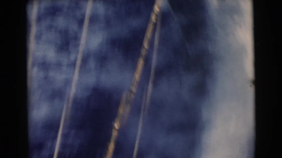 1956 Miami 8mm frame with blurred blue water, diagonal tow lines, foamy wake, and a partial piece of water-ski equipment.