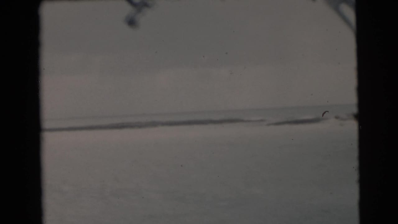 Calm water and low horizon seen through dark film-frame edges.