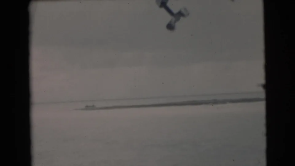 1956 Miami-area 8mm frame with a small distant boat on calm water, seen through dark vertical frame edges.