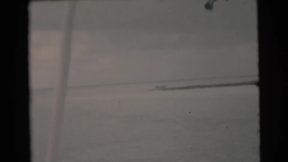 Boat-view 8mm footage from the Miami area, with open water, a faint distant boat, and a soft vertical foreground edge.