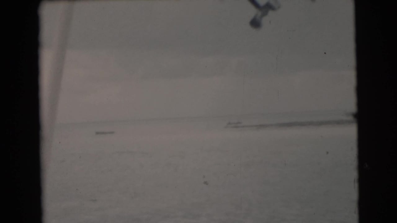 Calm ocean horizon under an overcast sky, seen through dark film-frame borders.