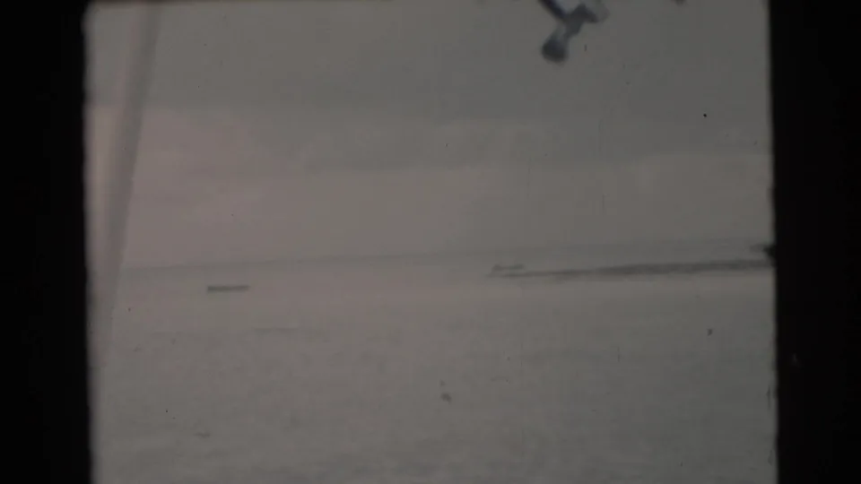 1956 Miami-area 8mm frame showing a calm ocean horizon beneath a muted cloudy sky, with no people or landmarks visible.
